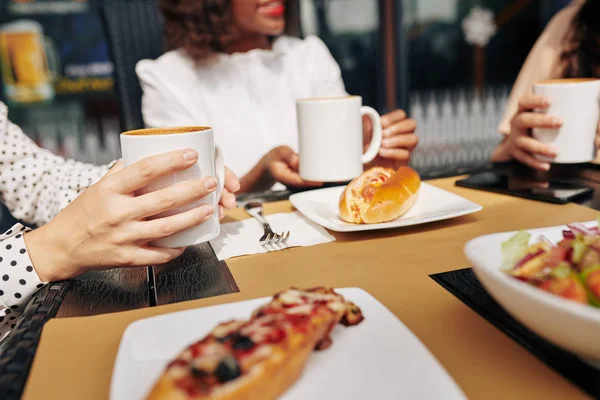 Close-up image of young woman meeting with friends in cafe, eating lunch and drinking coffee