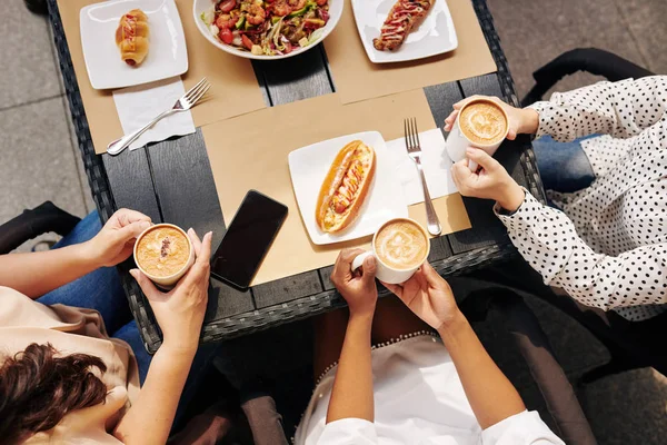 Imagem Cortada Amigas Comendo Almoço Saboroso Bebendo Grandes Canecas Cappuccino — Fotografia de Stock