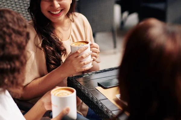 Cropped image of female friends meeting in coffeeshop and discussing news and gossips