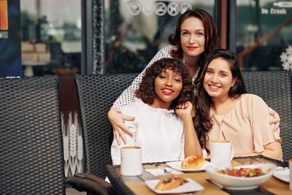 Sorrindo Bela Jovem Abraçando Seus Melhores Amigos Sentados Mesa Café — Fotografia de Stock