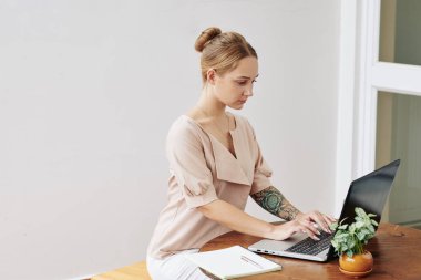 Dizüstü bilgisayarda ve evde çalışan ve ders kitabına not alan güzel bir kız öğrenci.