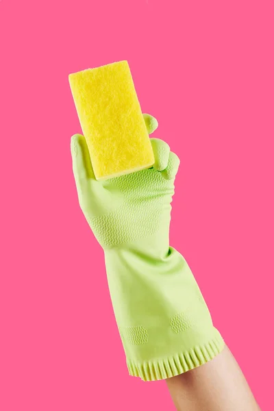 Gloved hand of housewife cleaning with kitchen soap, isolated on pink