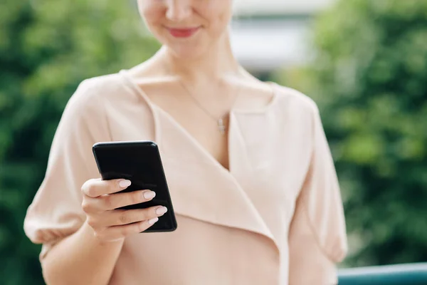 笑顔の若い女性のトリミングされた画像スマートフォンで友人からのテキストメッセージを読む — ストック写真