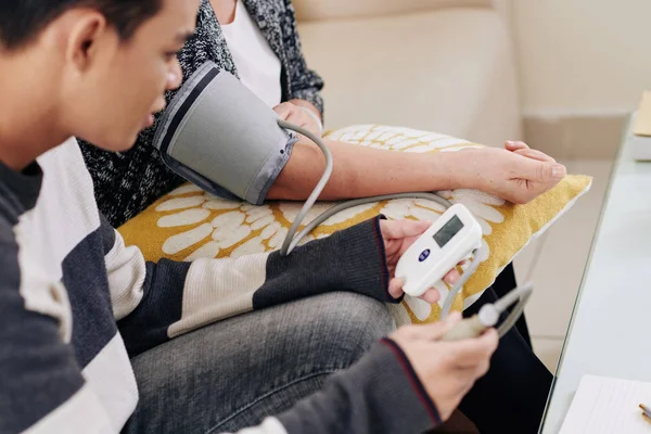 Volwassen Zoon Helpt Moeder Bloeddruk Meten Met Een Moderne Sfygmomanometer — Stockfoto