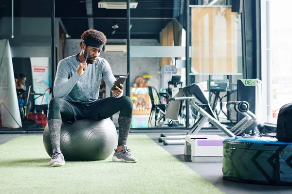 Tiro Horizontal Del Hombre Afroamericano Sentado Pelota Del Gimnasio Viendo —  Fotos de Stock