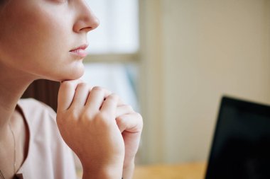 Yatay olarak yakın çekim. Çekici genç bir kadının çenesini ellerinin üzerinde dinlendirirken bir şey düşünürken.