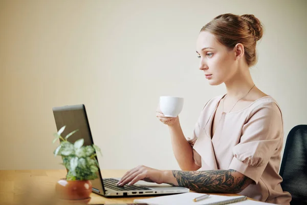 Elegancka Młoda Kobieta Tatuażem Ramieniu Pracująca Laptopie Biurze Pijąca Kawę — Zdjęcie stockowe