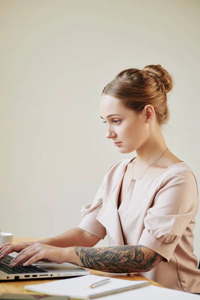 白种人妇女坐在写字台前 在笔记本电脑上认真工作 表情严肃的画像 — 图库照片