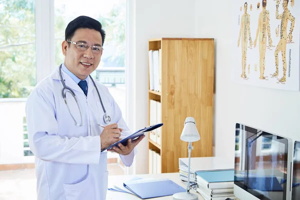 Médico Asiático Vistiendo Bata Blanca Estetoscopio Alrededor Cuello Escribiendo Algo —  Fotos de Stock