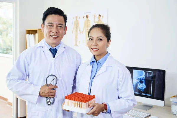 二人のアジアの医療従事者の水平肖像カメラを見て試験管とオフィスに立って — ストック写真