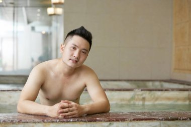 Yakışıklı genç adamın yatay portresi jakuzide kameraya bakarak zaman geçiriyor.