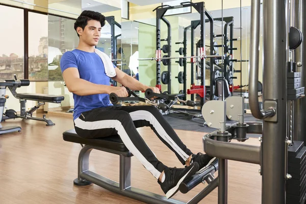 아시아 청년이 리조트 체육관에서 기계를 사용하여 운동을 스톡 사진
