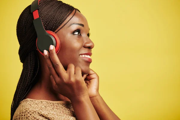 带着耳机欣赏音乐的年轻黑人妇女的横向头像和肩像 黄色背景 — 图库照片