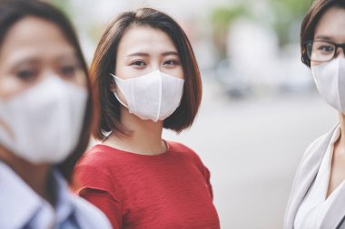 Kirlenmiş ya da enfekte olmuş şehrinin caddesinde duran tıbbi maskeli güzel Vietnamlı kadınların portresi.