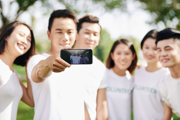 Junger Lächelnder Freiwilliger Der Mit Freunden Auf Dem Smartphone Fotografiert — Stockfoto