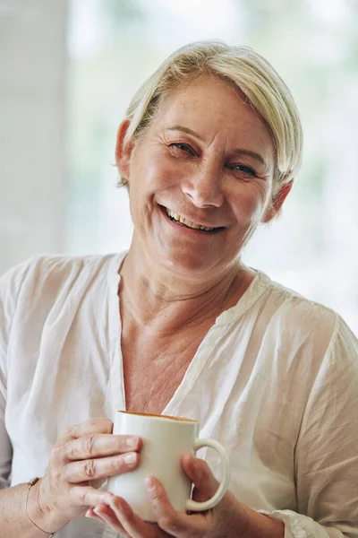一个微笑的成熟女人拿着一大杯早茶的画像 — 图库照片
