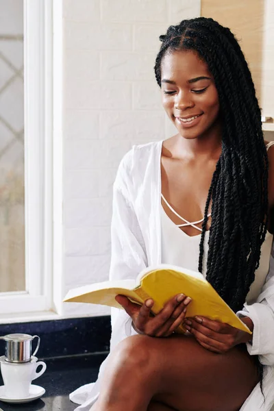 Gülümseyen Genç Siyah Kadın Sabah Kahvesini Içiyor Kitap Okuyor — Stok fotoğraf