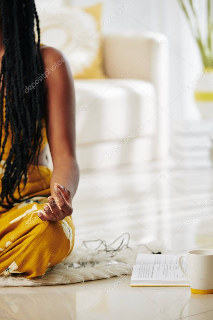 Cropped image of woman practicing meditation at home after reading book with affirmations
