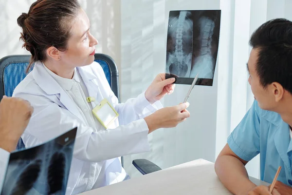 Mujer Joven Seria Mostrando Radiografía Columna Curvada Compañeros Trabajo Discutiendo — Foto de Stock