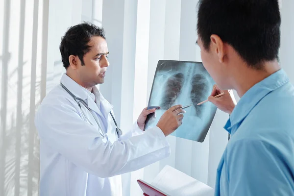 同僚に肺のX線を示す深刻な医師とコロナウイルスや肺炎の可能性のあるケースを議論 — ストック写真