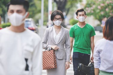 Sokakta virüslere ve hastalıklara karşı yürüyen tıbbi maskeli güzel bir Asyalı kadın.