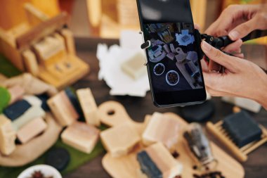Ekranda iş yerinin fotoğrafı ve sabun yapımında kullanılan malzemelerle birlikte akıllı telefon.