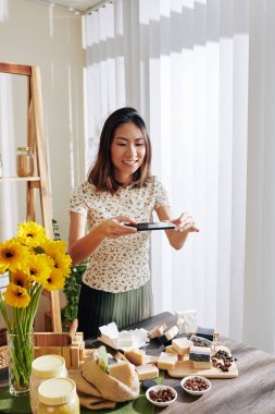 Neşeli, güzel, Vietnamlı bir kadın. İnternetteki dükkanı için yaptığı sabunu fotoğraflıyor.