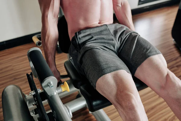 Cropped image of young man doing leg extension for quadriceps in gym machine