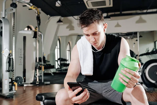 Ajuste Joven Poniendo Música Teléfono Inteligente Beber Agua Con Vitaminas —  Fotos de Stock