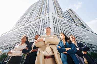 Ofis binasının önünde kolları bağlı duran başarılı iş ekibi.