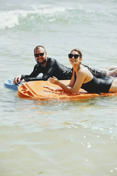 海で一緒にプラスチック製のマットレスで泳ぐのを楽しむ陽気な若い男性と女性 — ストック写真