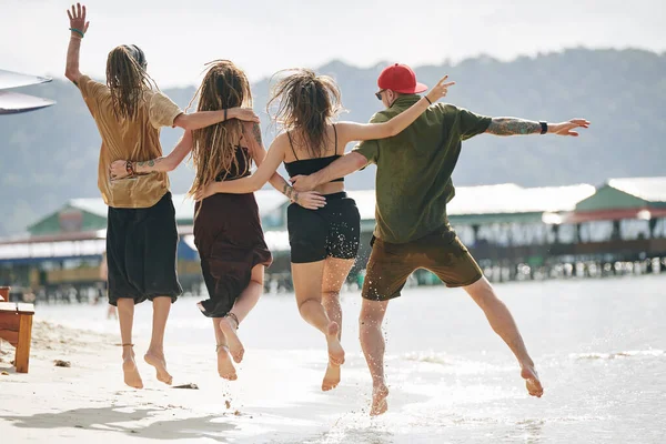 Grupo Amigos Empolgados Abraçando Saltando Praia Vista Das Costas — Fotografia de Stock