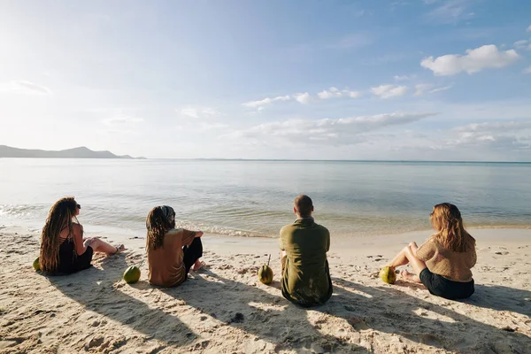 Grupo Amigos Sentados Praia Com Coquetéis Coco Olhando Para Águas — Fotografia de Stock