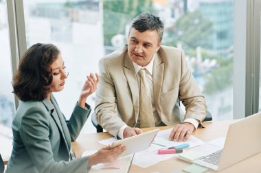 İş adamları geliştirme stratejisi üzerinde çalışırken tablet bilgisayarda rapor tartışırlar