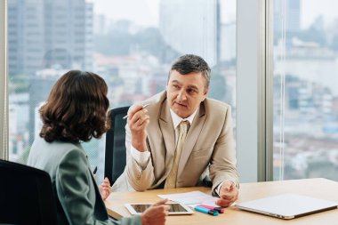 Proje yöneticileri yeni fikirleri ve yeni projenin ayrıntılarını köşedeki ofiste tartışıyorlar.
