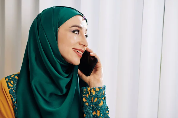 Koyu Yeşil Tesettürlü Gülümseyen Genç Müslüman Kadın Pencerenin Perdelerinden Bakıyor — Stok fotoğraf
