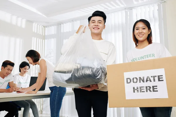 Paketler Kutular Dolusu Bağışlanmış Kıyafetlerle Poz Veren Genç Asyalı Gönüllüler — Stok fotoğraf