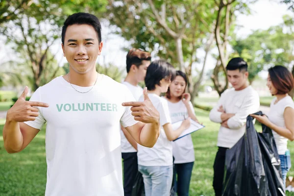 Sonriente Joven Vietnamita Apuntando Inscripción Voluntaria Camiseta Mientras Equipo Distribuye — Foto de Stock