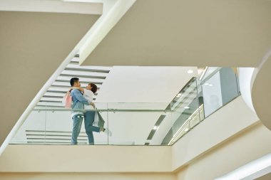İndirimli kıyafet ve ayakkabı aldıktan sonra alışveriş merkezinin balkonunda dikilen mutlu çift.