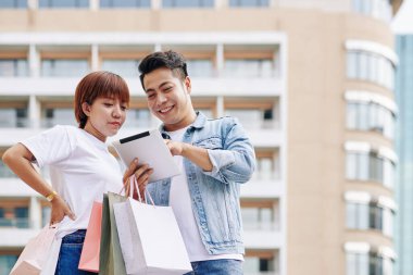 Mutlu genç Vietnamlı çift online alışveriş yaparken tablet bilgisayarda uygulama kullanıyor