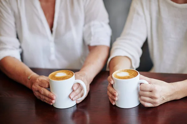 老妇人和她的成年女儿的手 喝着一大杯卡布奇诺 在咖啡店里聊天 — 图库照片