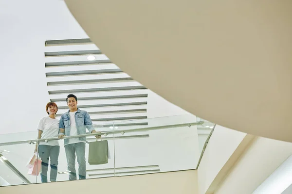 Fröhliches Junges Asiatisches Paar Mit Einkaufstüten Steht Auf Balkon Einkaufszentrum — Stockfoto