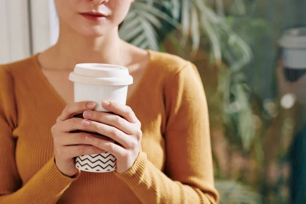 暖かいマスタードセーターで若い女性の手の中においしいコーヒーを取るの大きなカップ — ストック写真