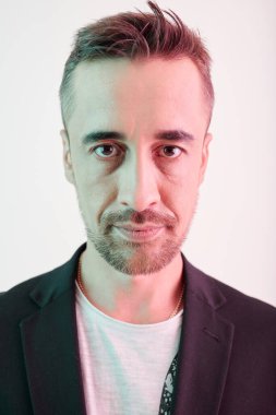 Sakallı ve kameraya bakan ciddi bir adamın portresi.