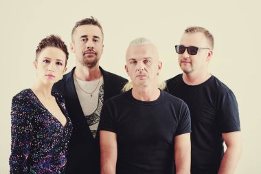 Konser kıyafeti giymiş ciddi müzik grubu üyelerinin grup fotoğrafı.