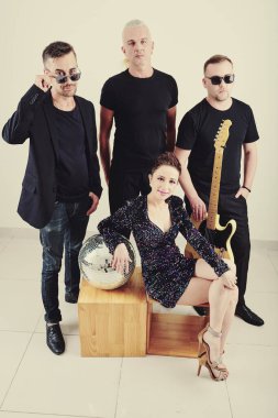 Gülümseyen güzel bayan şarkıcı ve müzik grubu üyeleri stüdyoda poz veriyorlar.