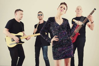 Parlak kısa elbiseli güzel bir kadın mikrofon tutuyor ve müzik eşliğinde dans ediyor.