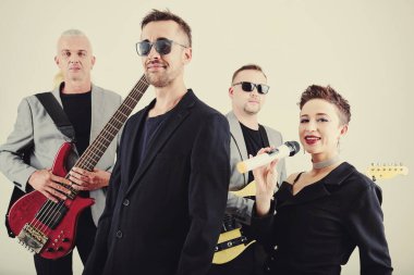 Gülümseyen stil sahibi popüler müzisyenler gitar çalıyor ve konserde şarkı söylüyorlar.