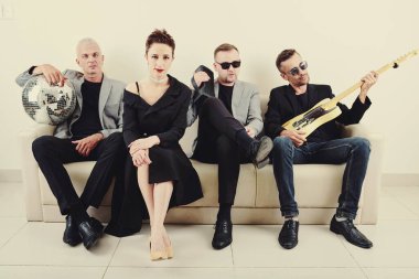 Müzik grubu üyeleri konserden sonra kanepede dinlenip müzik dinliyor. 