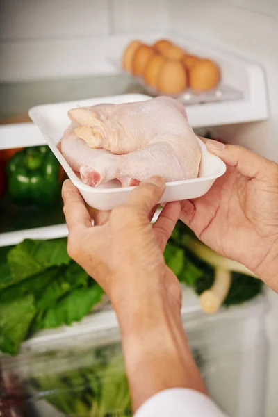 家で夕食を作るときに冷蔵庫から冷蔵庫から鶏を取る人の手 — ストック写真